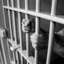 Image of prisoner's hands gripping bars of cell