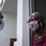 This is a photo showing a census worker speaking with an apartment building resident