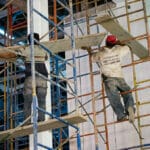 Photo of two workers on construction site doing dangerous work