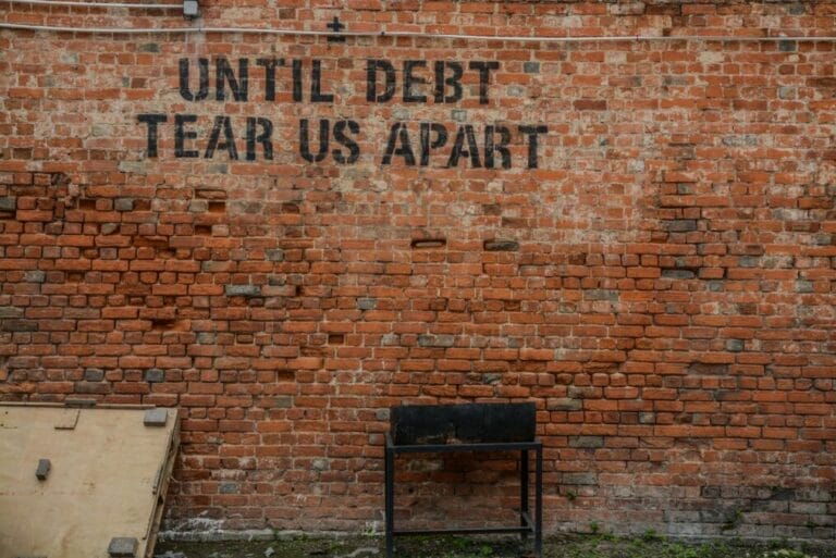 Image of brick wall with words 'Until debt tear us apart.'
