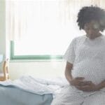 Photo of pregnant woman sitting on bed