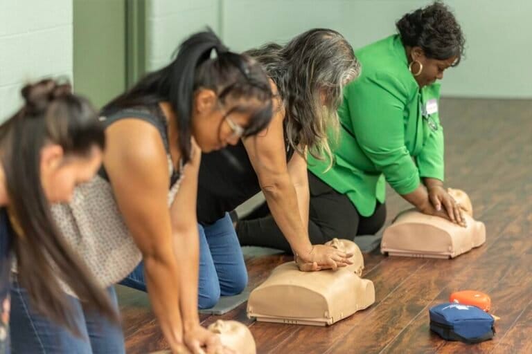 Photo of four mothers practicing CPR on partial child mannequins