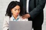 image of man massaging shoulder of woman seated at computer